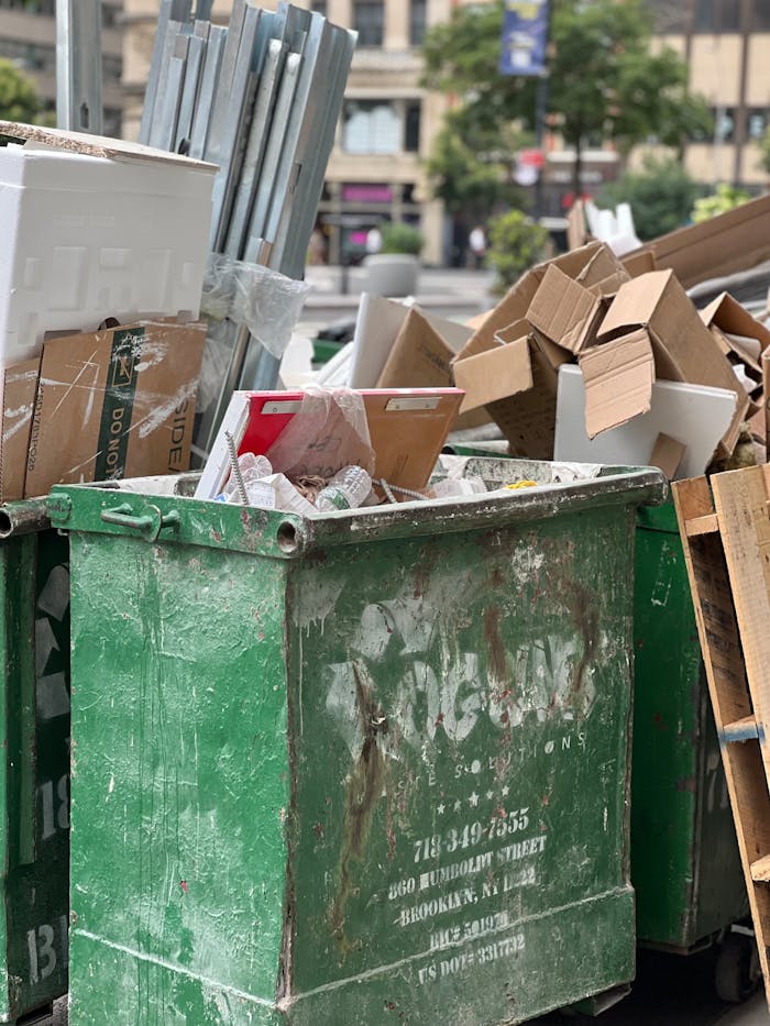 Home Overflowing dumpster with cardboard and various waste in urban setting.